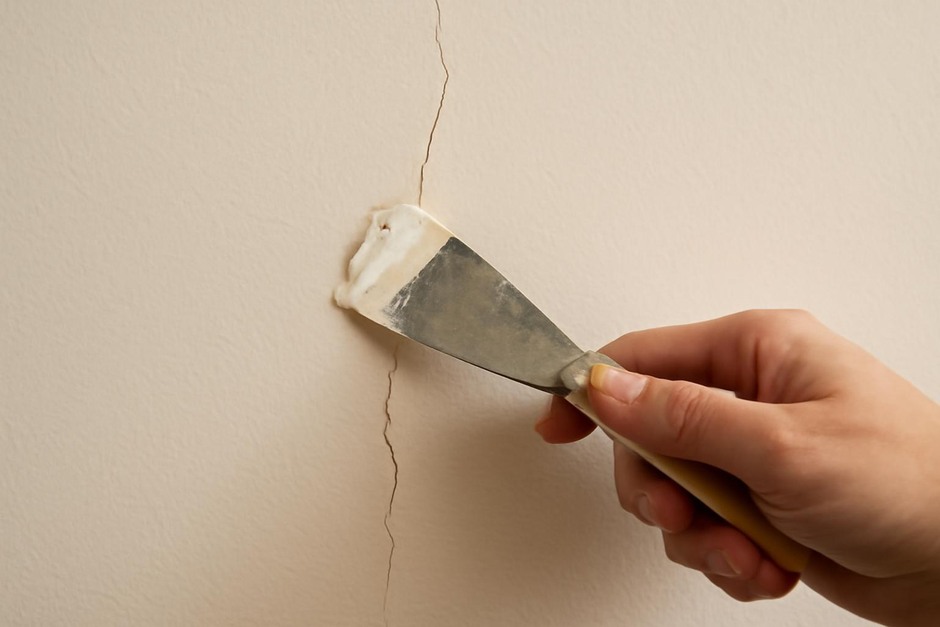Close-up of a hairline crack in interior plaster being repaired