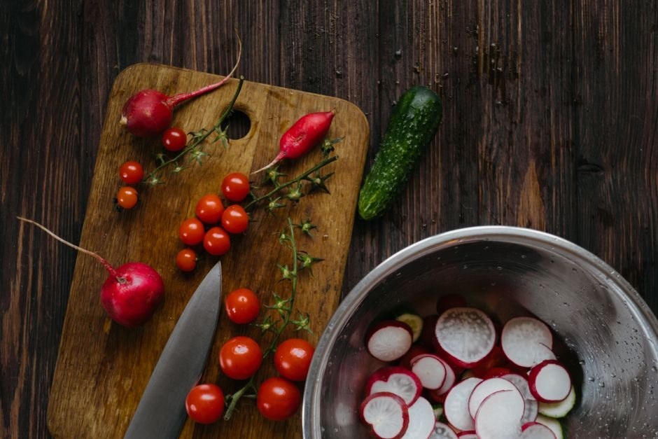 Fresh tomatoes, radishes and cucumber prepared on a wooden kitchen table